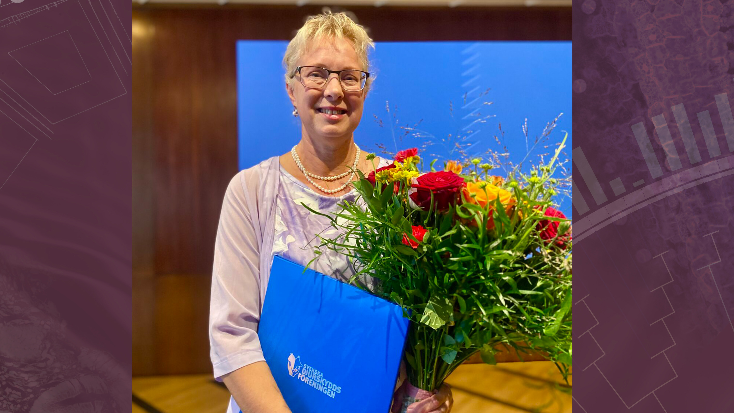 Professor Lotta Berg som fått pris som årets djurvän 2025. Lotta håller i en blombukett och en prismapp. 