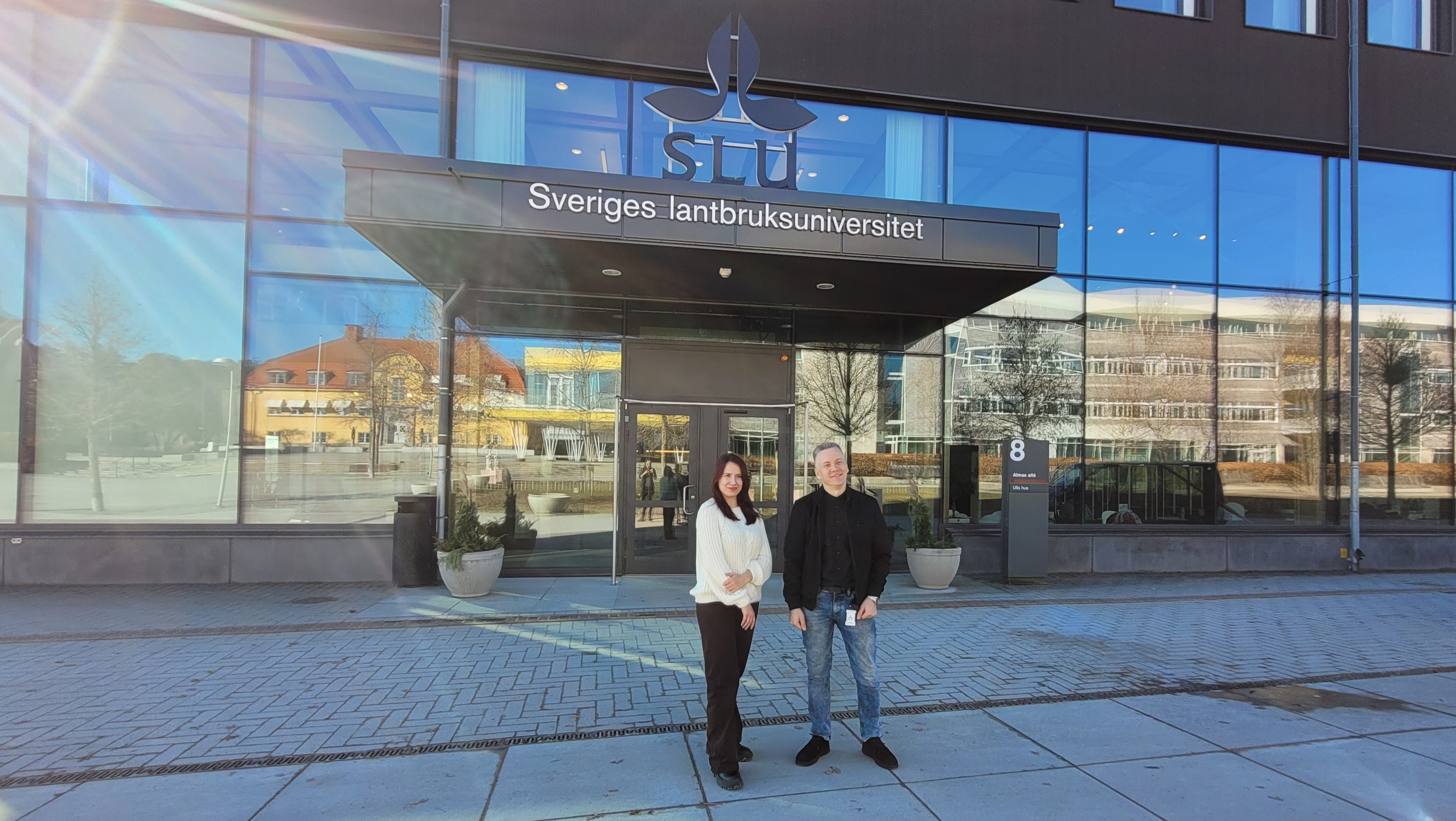 Två personer framför SLUs entré