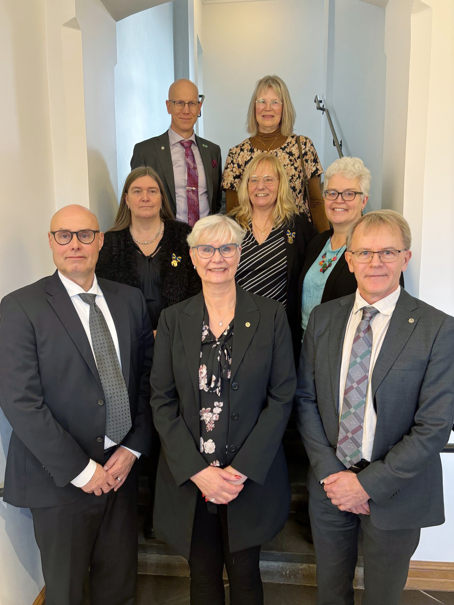 En grupp glada människor som står i ett trapphus inomhus