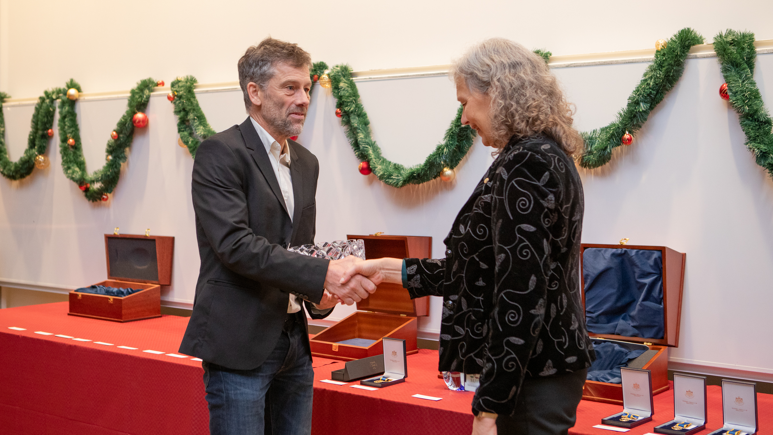 En man tar emot en gåva och skakar hand med en kvinna.