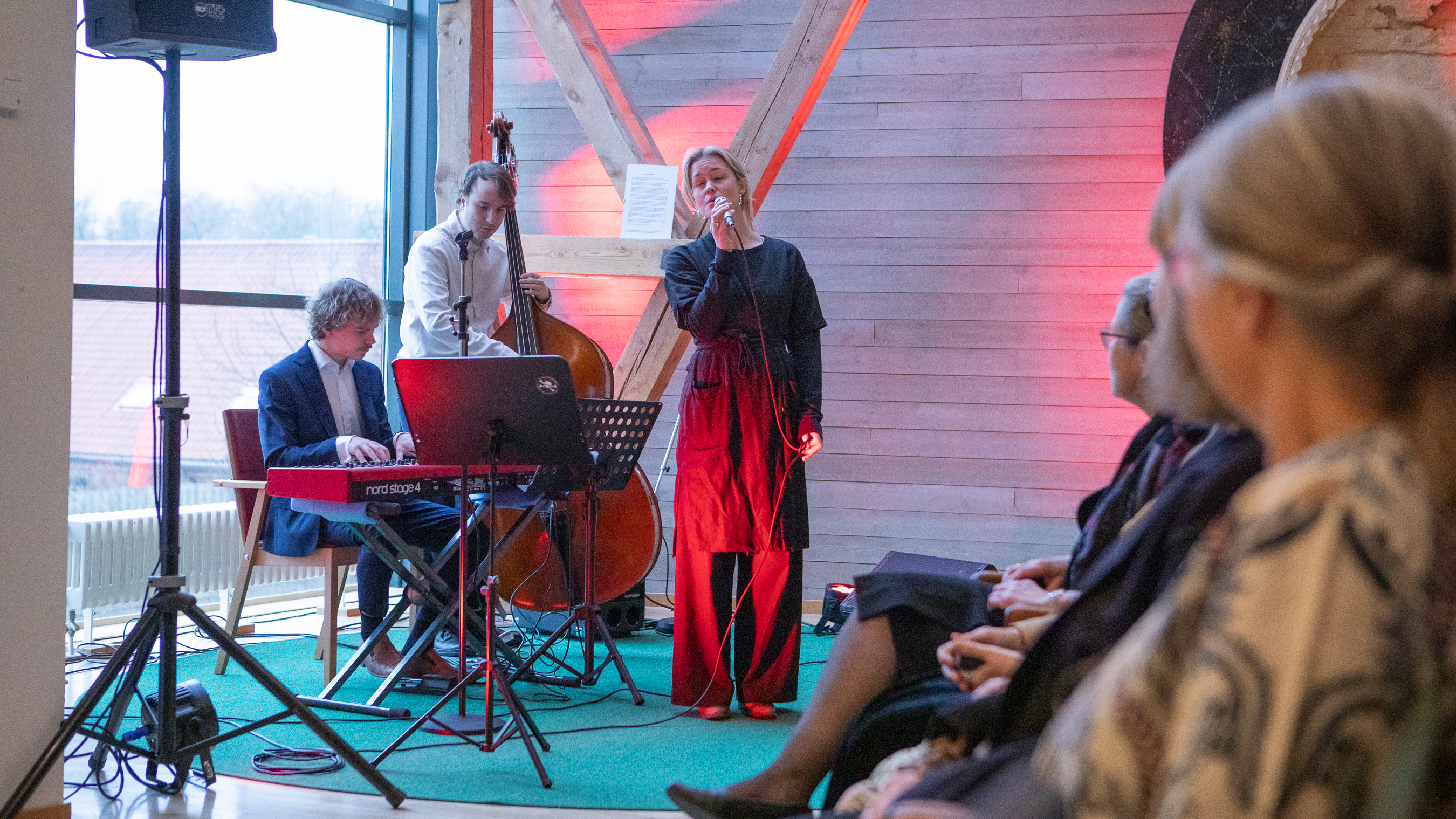 En trio med sångerska, pianist och basist uppträder..