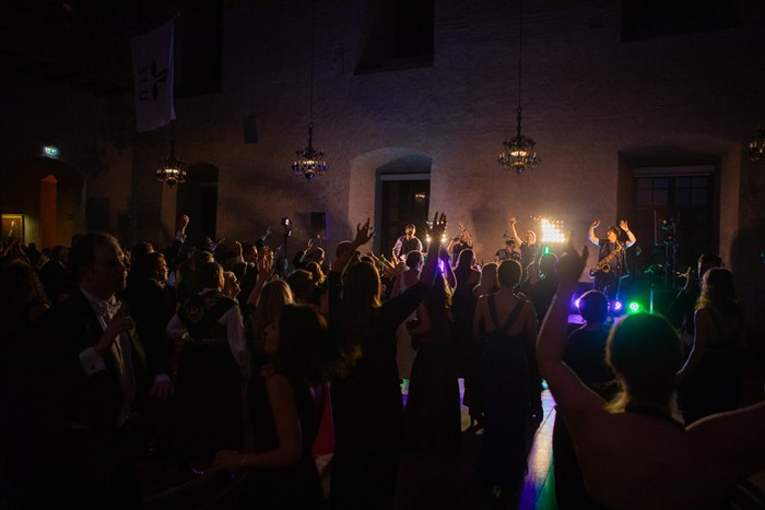 Dancing people in front of a brightly lit stage. Hands in the air. 