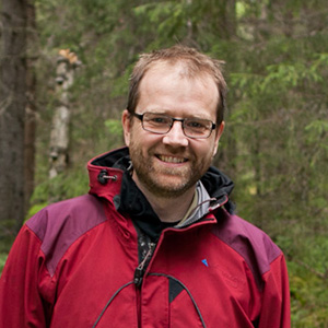 Hjalmar Laudon i röd jacka i en skog. Foto.