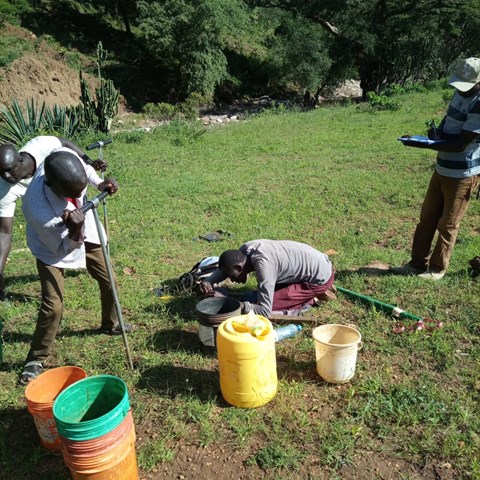 Field workers collecting soil samples and measuring infiltration