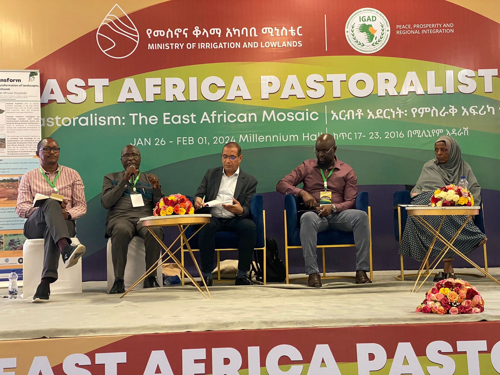 Four men and one woman sits on a podium during a panel discussion