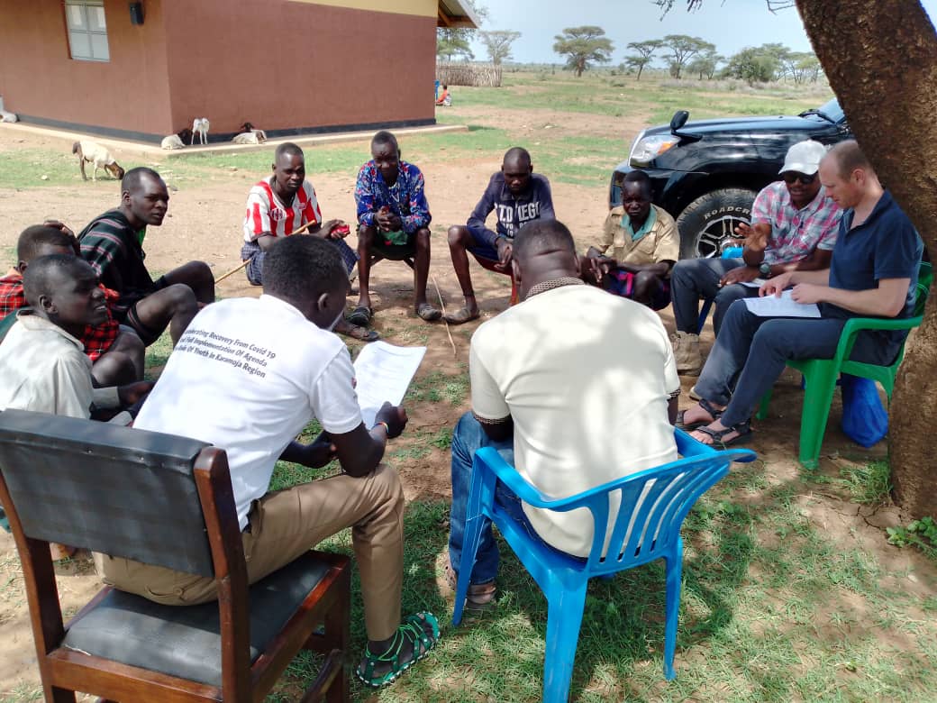 Men sits in a circle under a tree