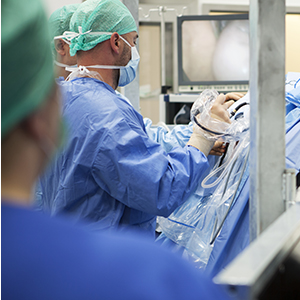 Tre personer med operationskläder arbetar. Foto.