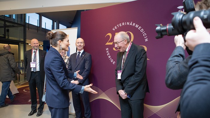 H.K.H. Kronprinsessan Victoria hälsar muntert på professor Henrik Elvang Jensen, den första mottagaren av Stora forskningspriset i veterinärmedicin. I bakgrunden står Jens Kisling, Danmarks ambassadör i Sverige och längst till vänster Nils Fall, dekan för fakulteten för fakulteten för veterinärmedicin och husdjursvetenskap. 