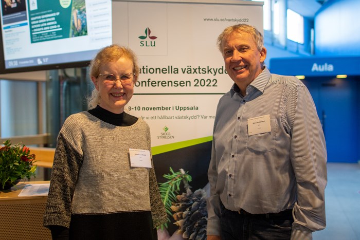 En man och en kvinna står framför en roll-up där det står Nationella växtskyddskonferensen 2022. Foto.