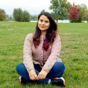 En ung dam sitter med korslagda ben på en gräsmatta, foto.