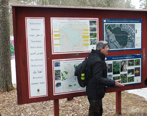 Nature guide in front of a welcome board at a nature reserve. Photo.