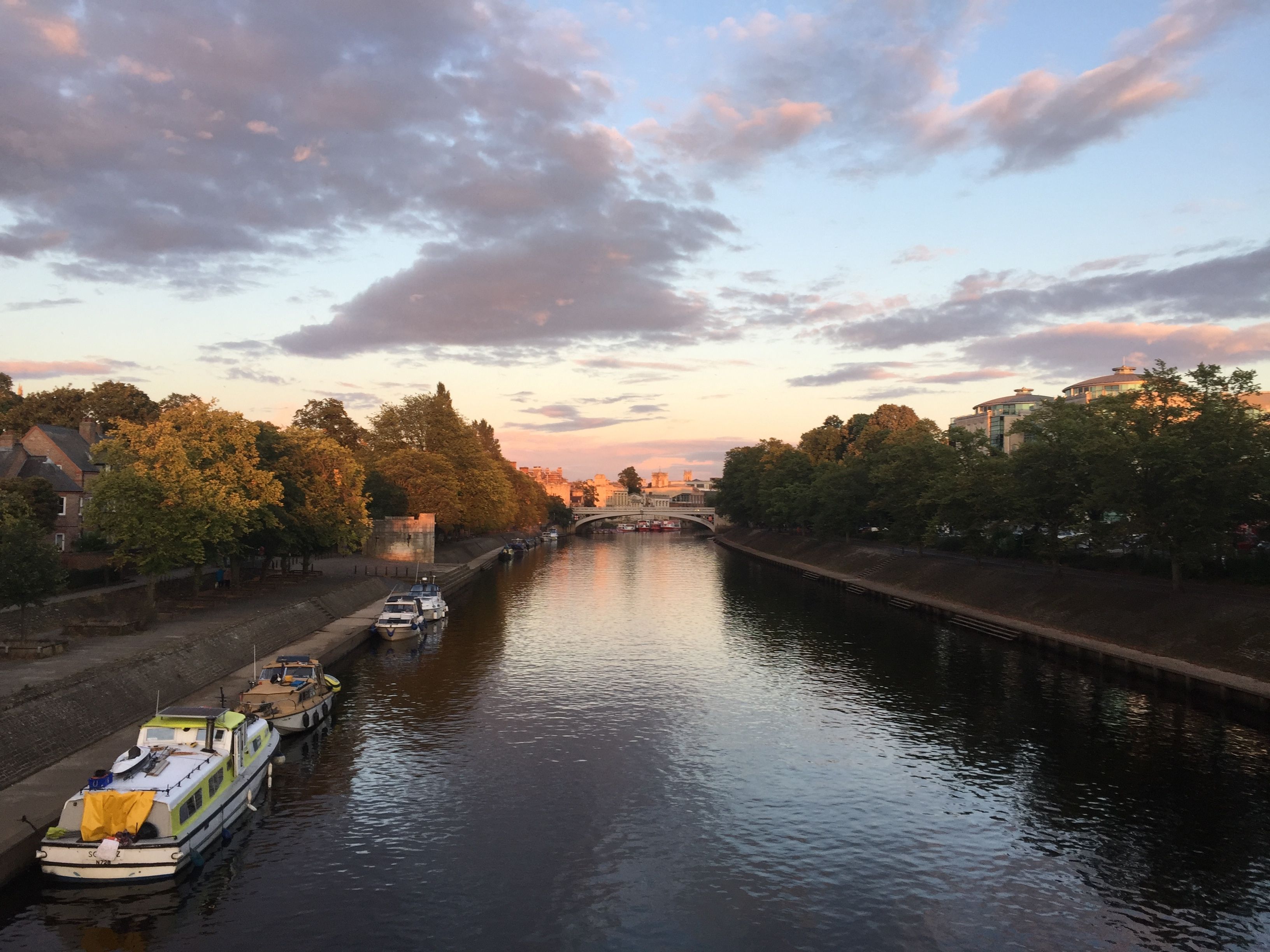 Bred flod med båtar vid ena strandkanten, foto.