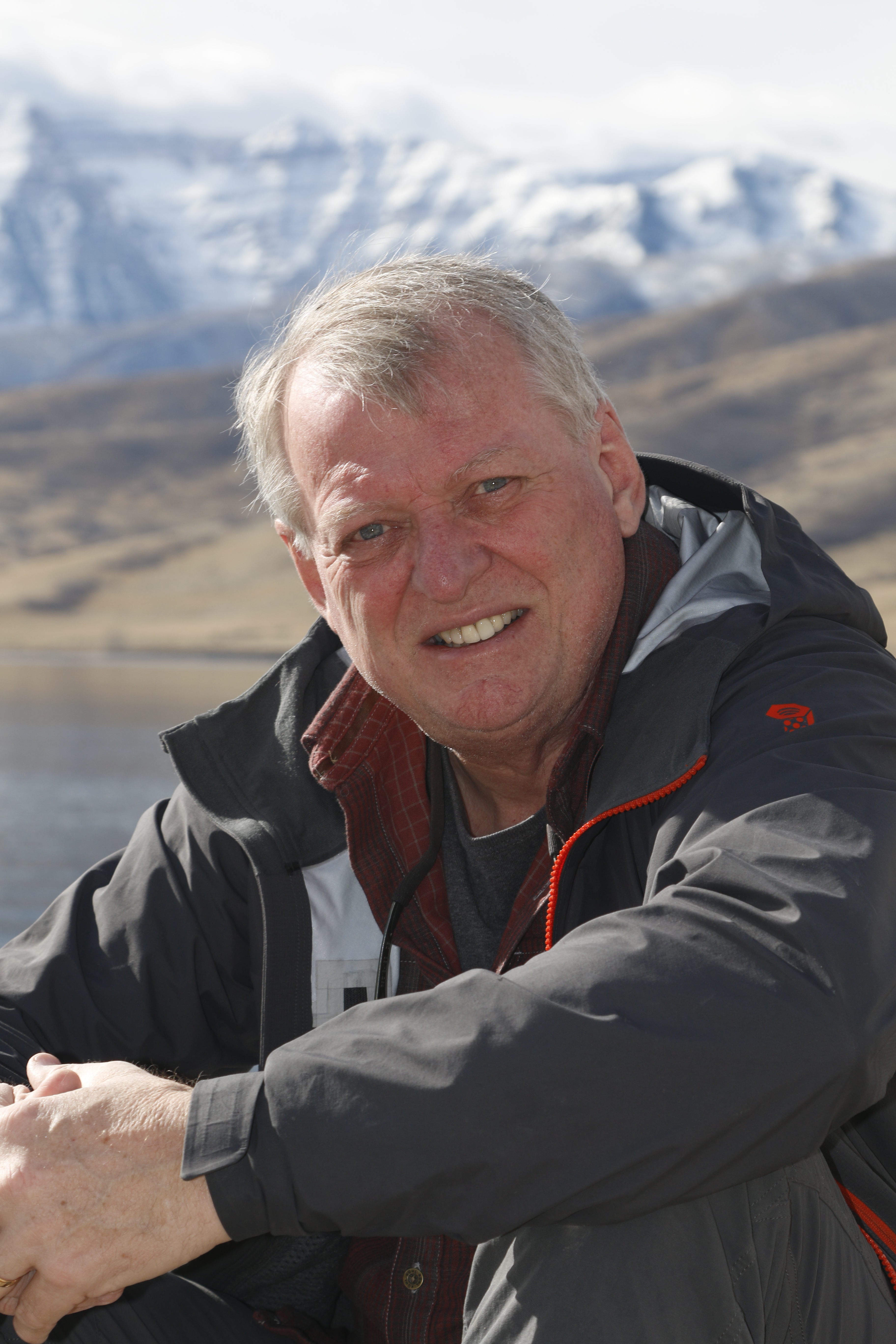 Bo Landin sitter vid en fjällsjö. Snötäckta fjäll syns i bakgrunden.