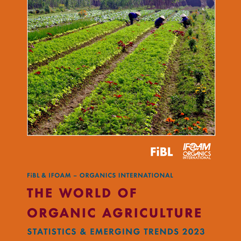 Framsida av FiBL:s årsbok 2023, orange bakgrund med en bild av tre människor som arbetar i ett grönt fält med inslag av blommor.