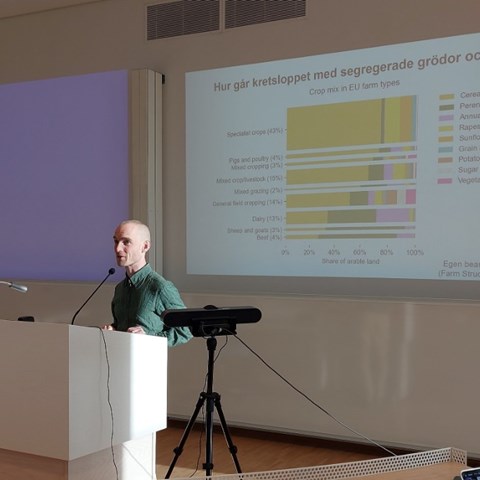 Rasmus Einarsson i grön tröja föreläser från en talarstol.
