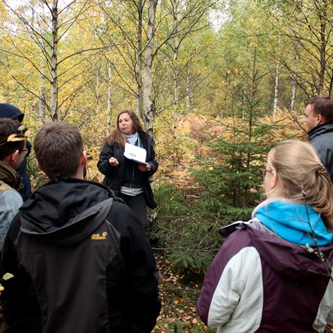 Emma Holmström föreläser inför en samling personer i skogen. Foto.