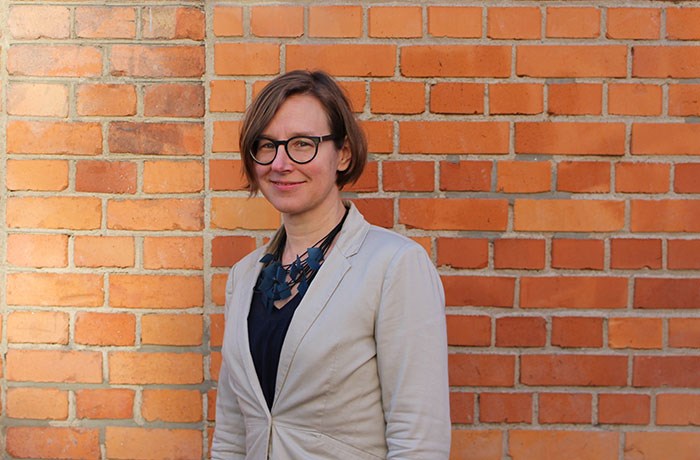 A woman in front of a brick wall. Photo.