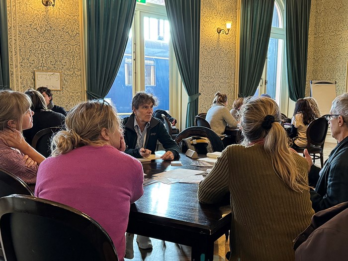 Group of people in conversation around a table.