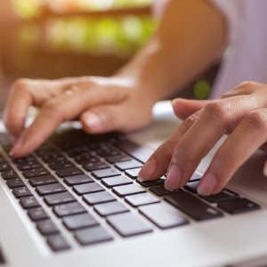 Hands writing on a laptop.