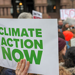 Someone is holding up a sign with the text "Climate Action Now" in a crowd of people