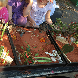 Barn leker med modeller i sand.