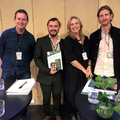 Four people smile at the camera behind standing tables at a conference.