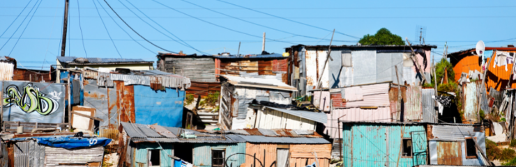 Informal settlement houses under a blue sky.