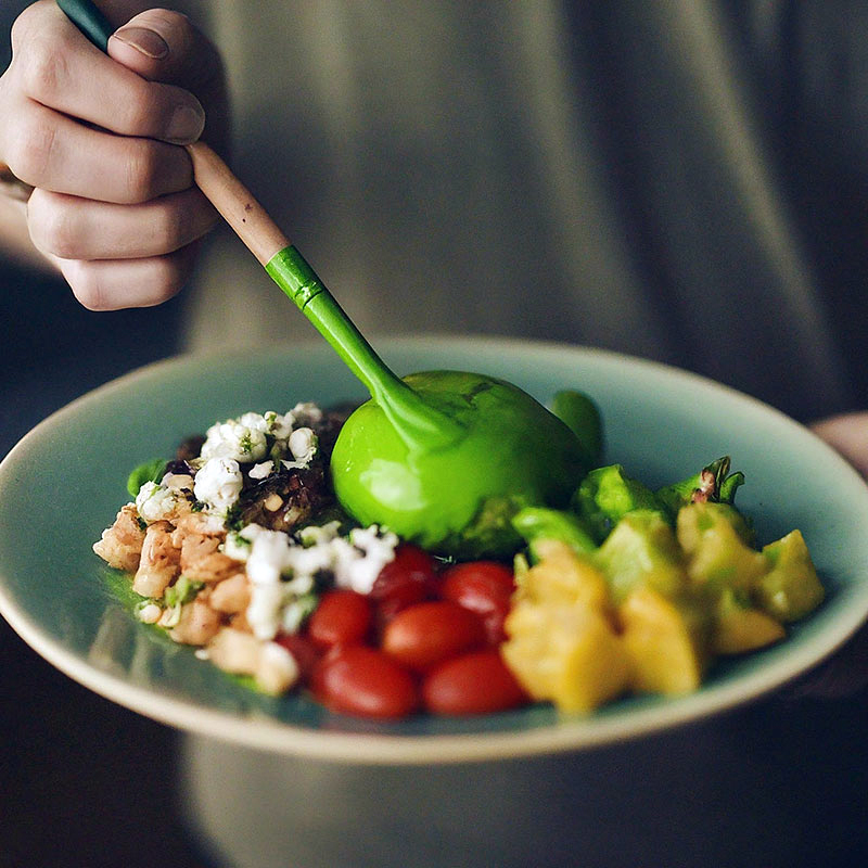 En hand målar grön färg på maten på en tallrik. Ai-genererad bild.