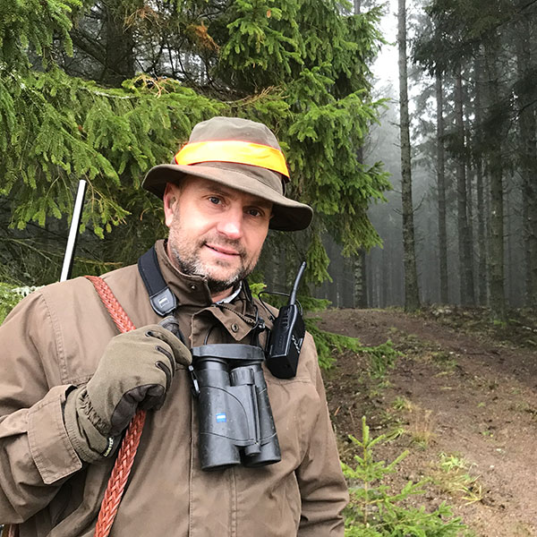 Bild på jägaren Martin i skogen, med kikare om halsen.