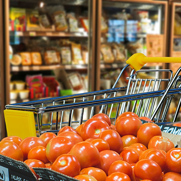Kundvagn, tomater och grönsaksdisk. Foto.