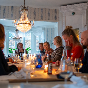 Personer vid ett bord under kristallkronor. Foto.