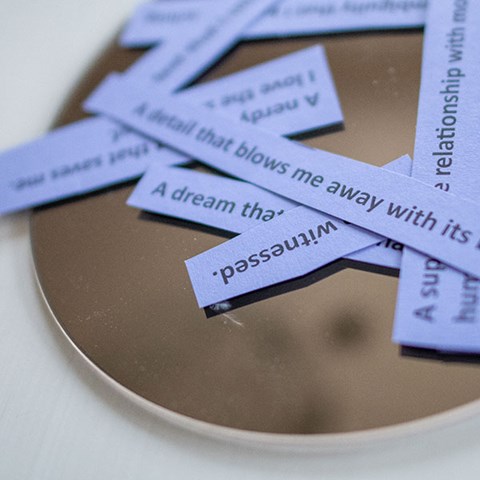 Small white paper notes with short texts lying on a round plate. Photo.