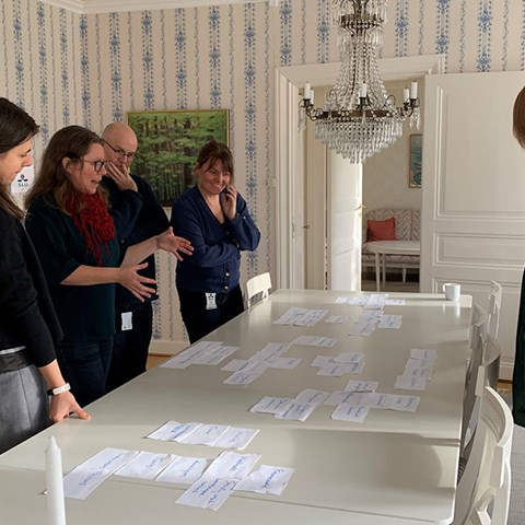 Grupparbete runt ett bord med postit-lappar, foto.