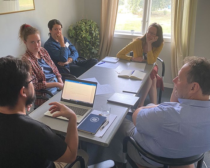 A small group of men and women sit on chairs around a table and have a discussion. Photo: Eva-Stina Lindell