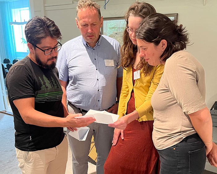 Four people stand next to each other and read a letter.