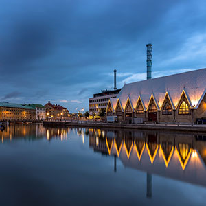 En kyrkliknande byggnad vid en å speglas i vattnet, foto.