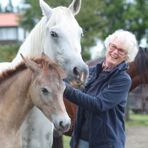 En kvinna och två hästar utomhus, foto.