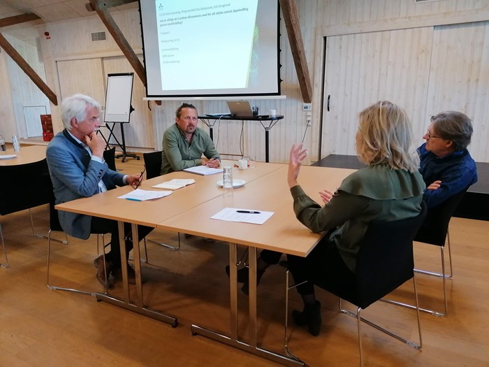 Fyra personer sitter runt ett bord och diskuterar på workshopen Växtförädling och äpple 2022.