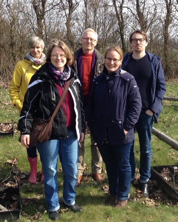 Nationella genbankens referensgrupp samlad ute i genbanken. Fem personer står framför humleodlingen i Nationella genbanken. Foto.