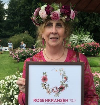 Helena Persson, samordnare för Pom, med rosenkrans i håret och diplom i famnen.