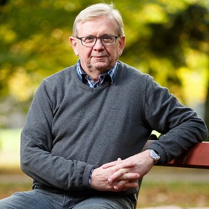 Man sitter på bänk i parken. Foto.