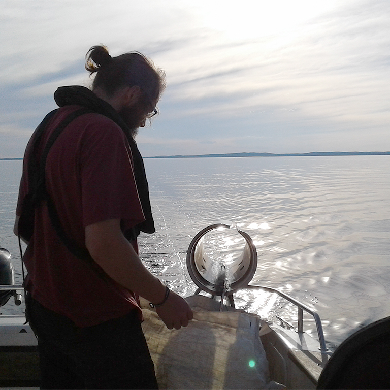 Man i aktern på en båt i solnedgång