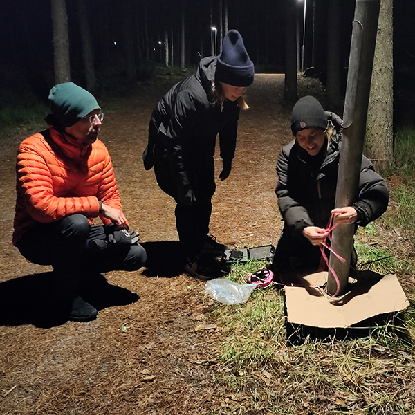 Tre personer på en stig i mörkret.