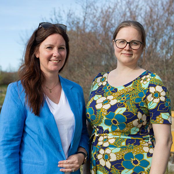 Två personer utomhus framför bigården