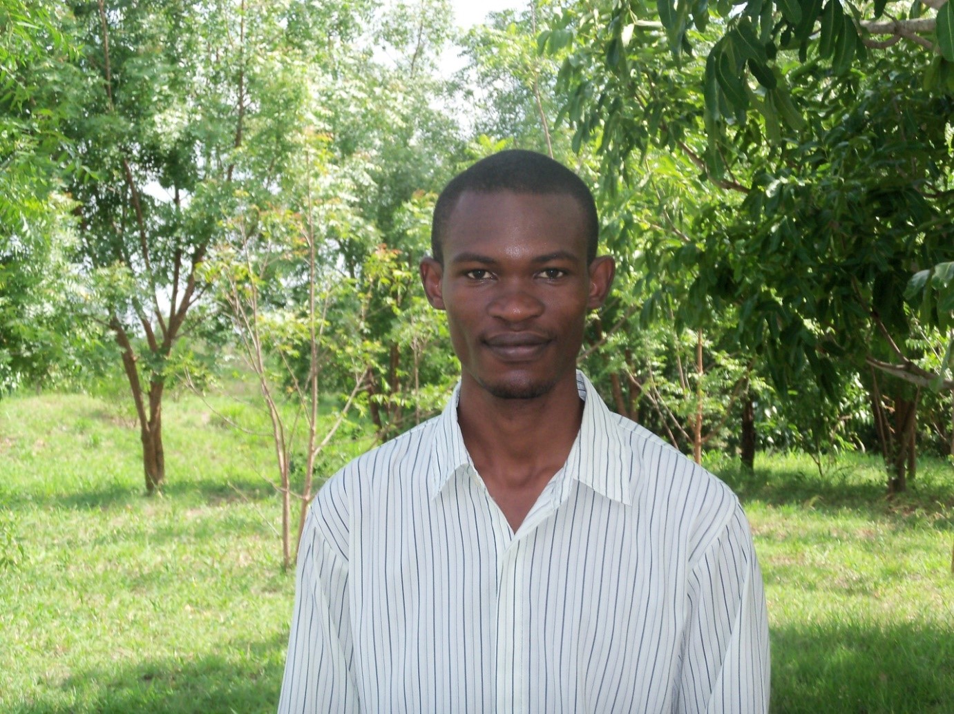 Bild på Peter Ruvuga med träd och gräs i bakgrunden. Foto. 
