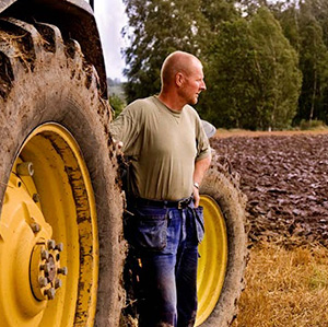Man vid traktordäck, ser ut över plöjt fält