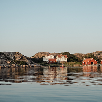 hav i förgrunden och klippor med stugor