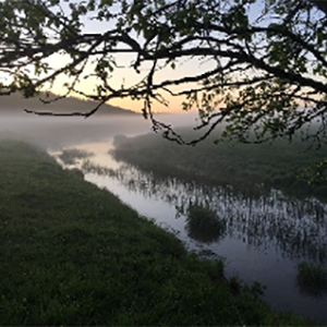 A river at sunrise with fog over. Photo.