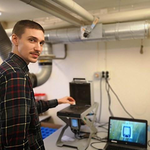 Phd student Karl Adler in front of an X-ray fluorescence device that he used working with his phd thesis.