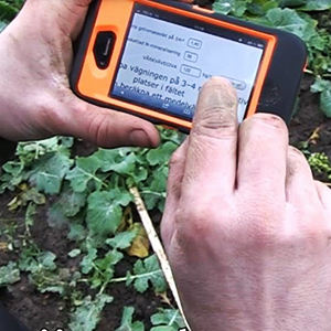 händer håller i en handdator ute i fält